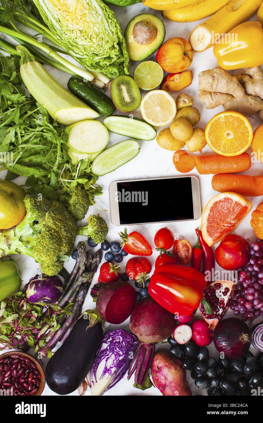 Concept de ferme frais de livraison des légumes biologiques et des fruits. Produits de la ferme, smartphone avec la nourriture vegan, vue du dessus Banque D'Images Concept de ferme frais de livraison des légumes biologiques et des fruits. Produits de la ferme, smartphone avec la nourriture vegan, vue du dessus Banque D'Images