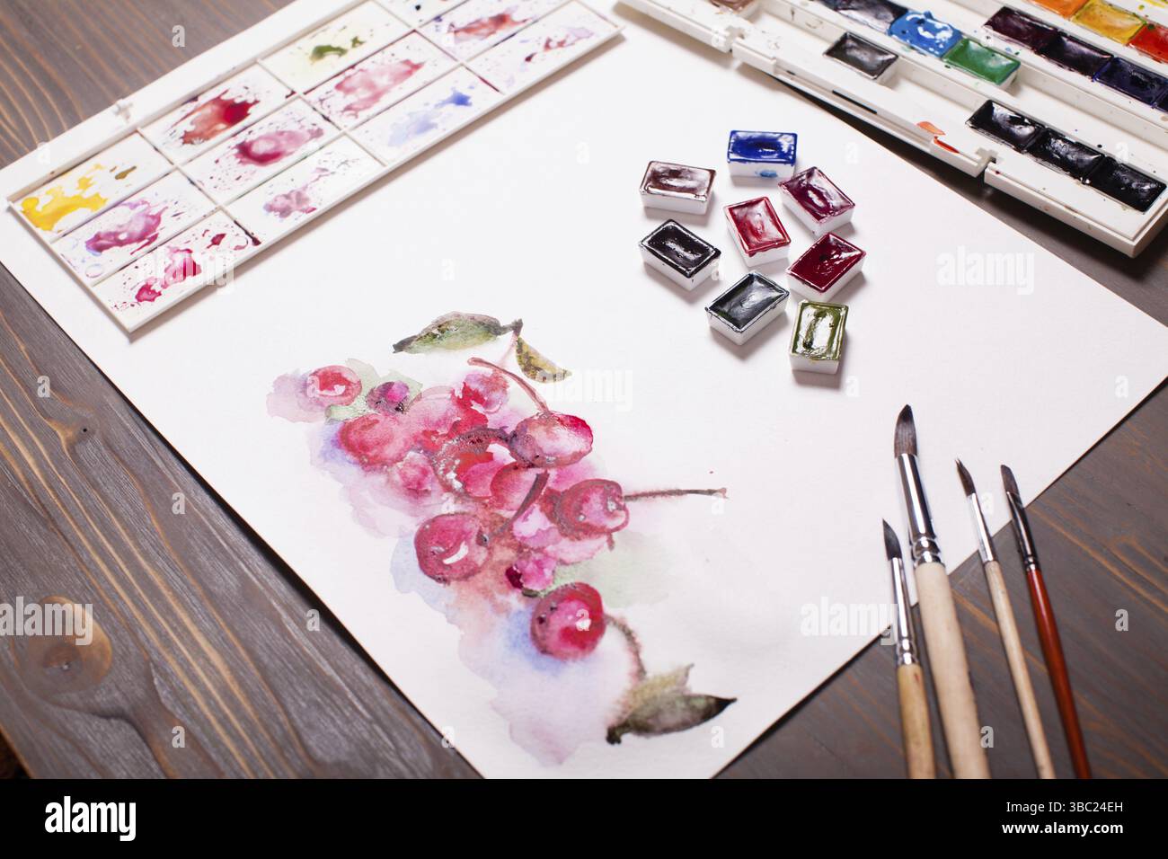 Œuvres d'art, peintures à l'aquarelle cerises avec outils de dessin sur une table en bois Banque D'Images