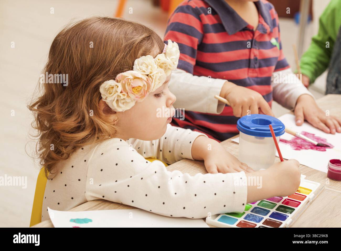 2 ans les enfants apprennent à peindre avec un pinceau et des aquarelles sur papier à la maternelle Banque D'Images