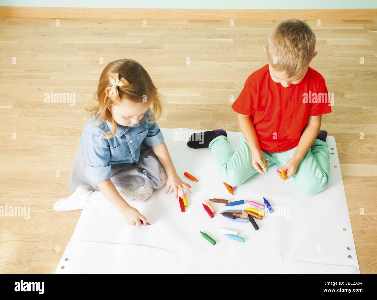 Les amis cute boy sur un sol en bois et le dessin avec des crayons de couleur Banque D'Images