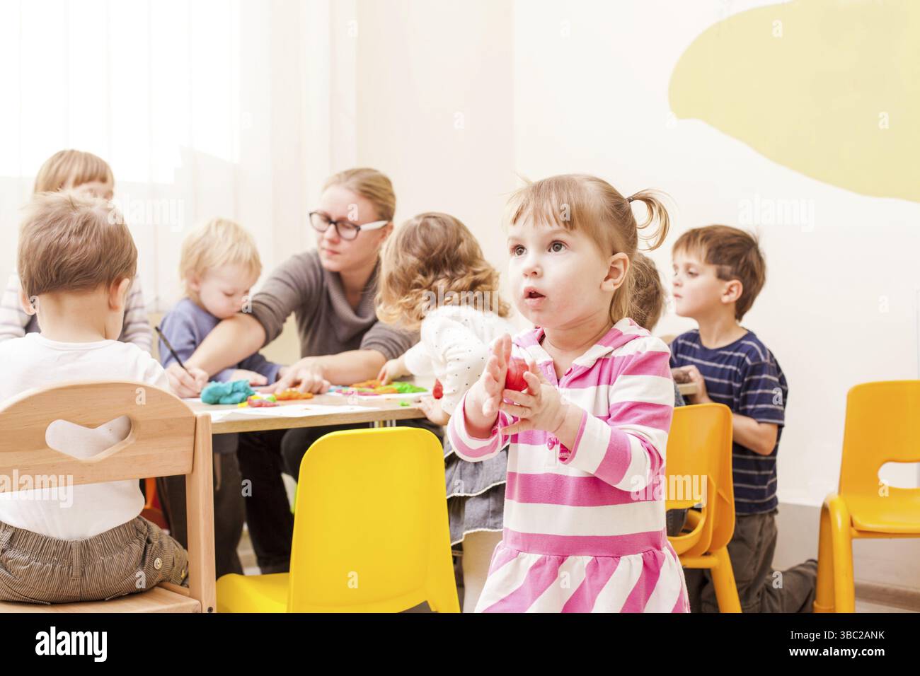 La fille fait une figure de plasticine près de la table Banque D'Images