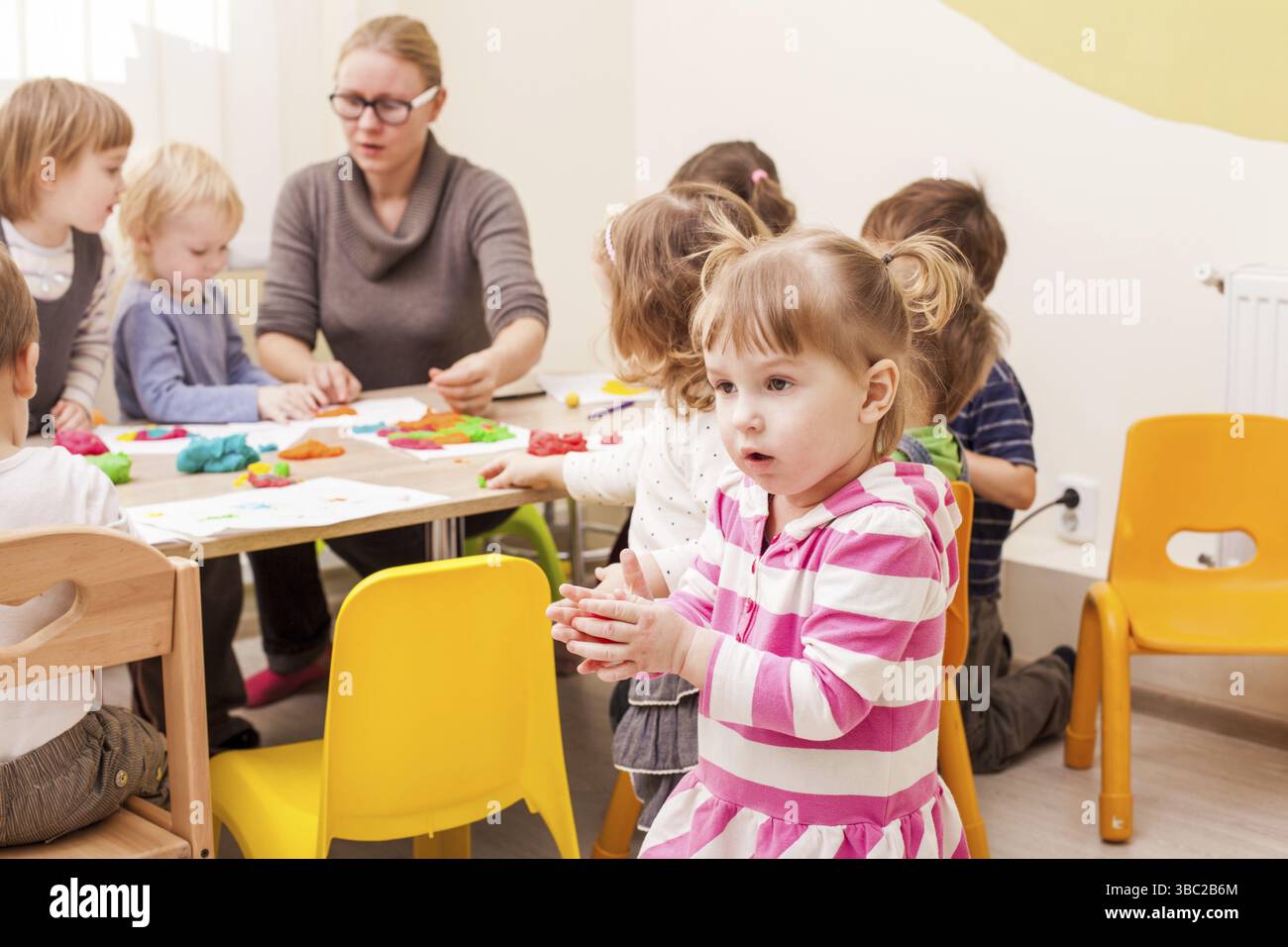 La fille fait une figure de plasticine près de la table Banque D'Images