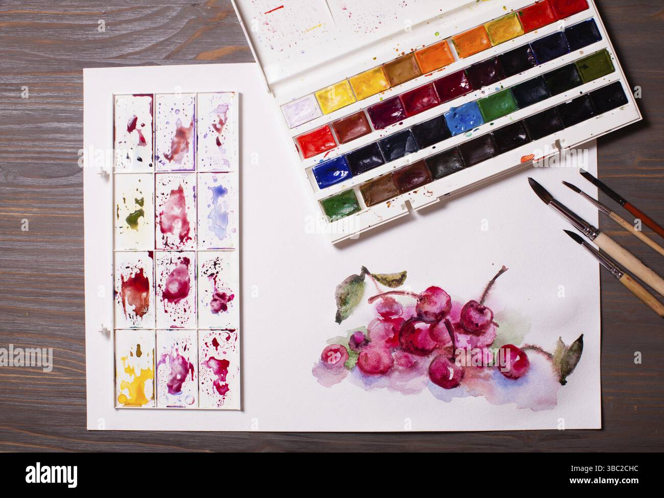 Œuvres d'art, peintures à l'aquarelle cerises avec outils de dessin sur une table en bois Banque D'Images