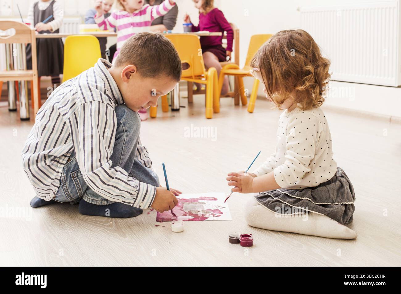 Les enfants sont la peinture avec un pinceau et d'aquarelles sur papier dans le jardin d'enfants Banque D'Images