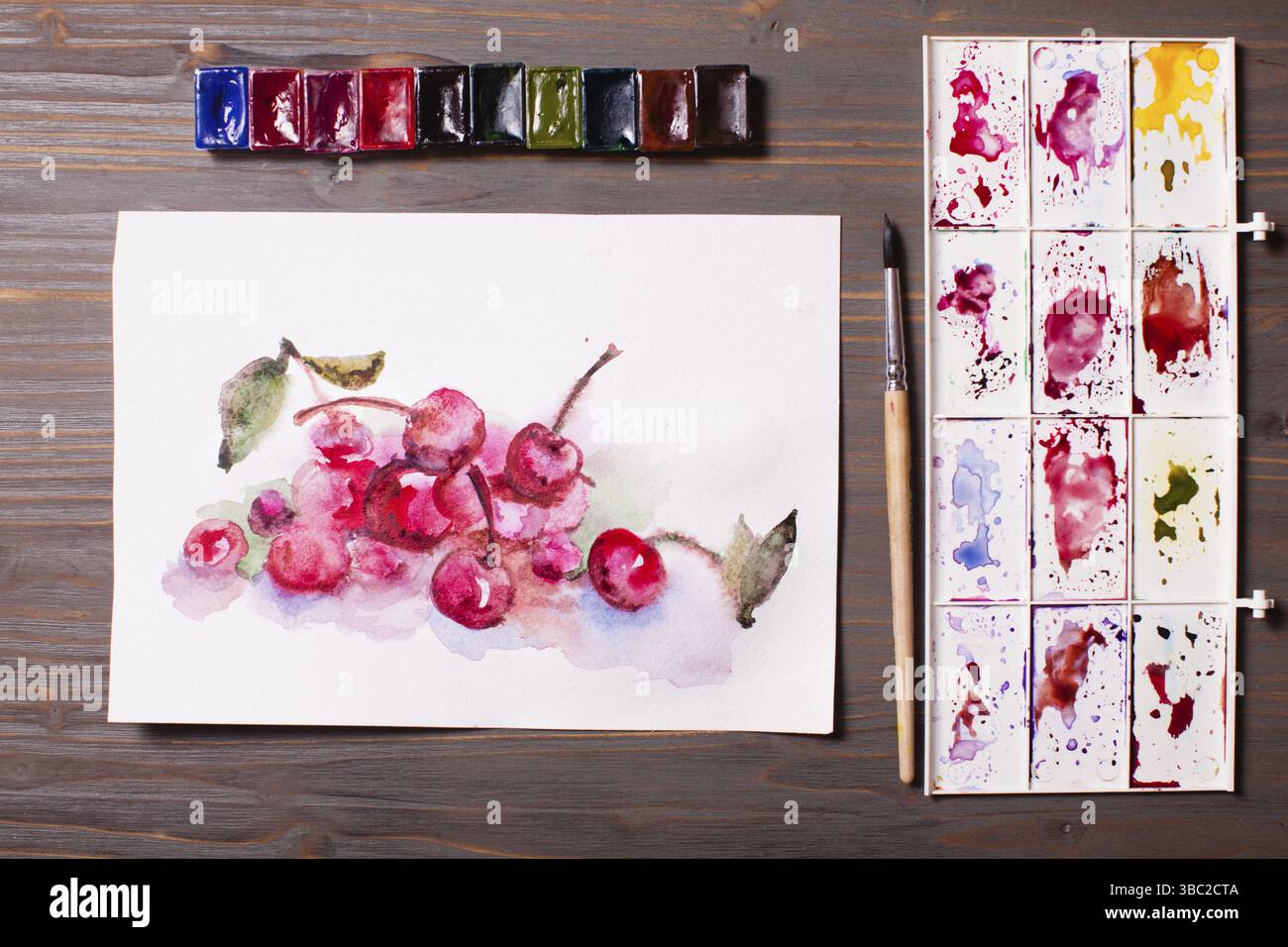 Œuvres d'art, peintures à l'aquarelle cerises avec outils de dessin sur une table en bois Banque D'Images