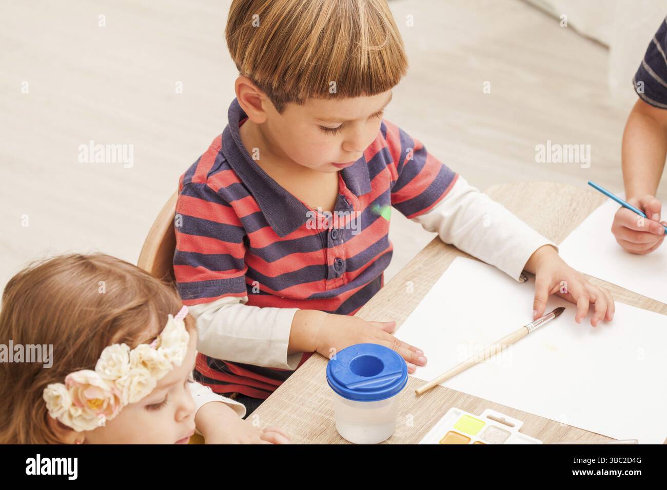 Les enfants apprennent à peindre avec un pinceau et des aquarelles sur papier à la maternelle Banque D'Images