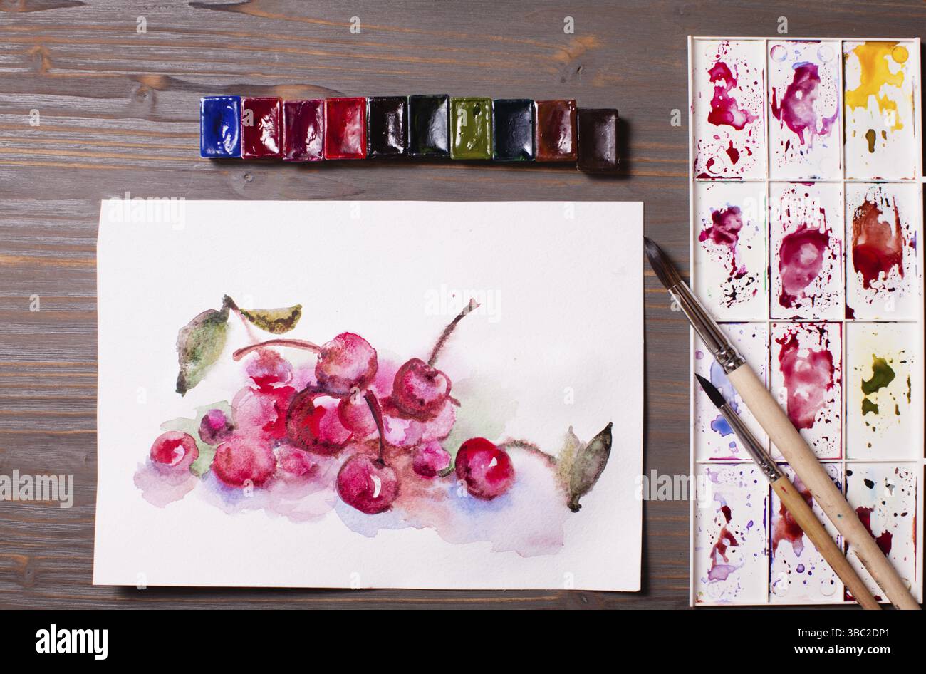 Œuvres d'art, peintures à l'aquarelle cerises avec outils de dessin sur une table en bois Banque D'Images