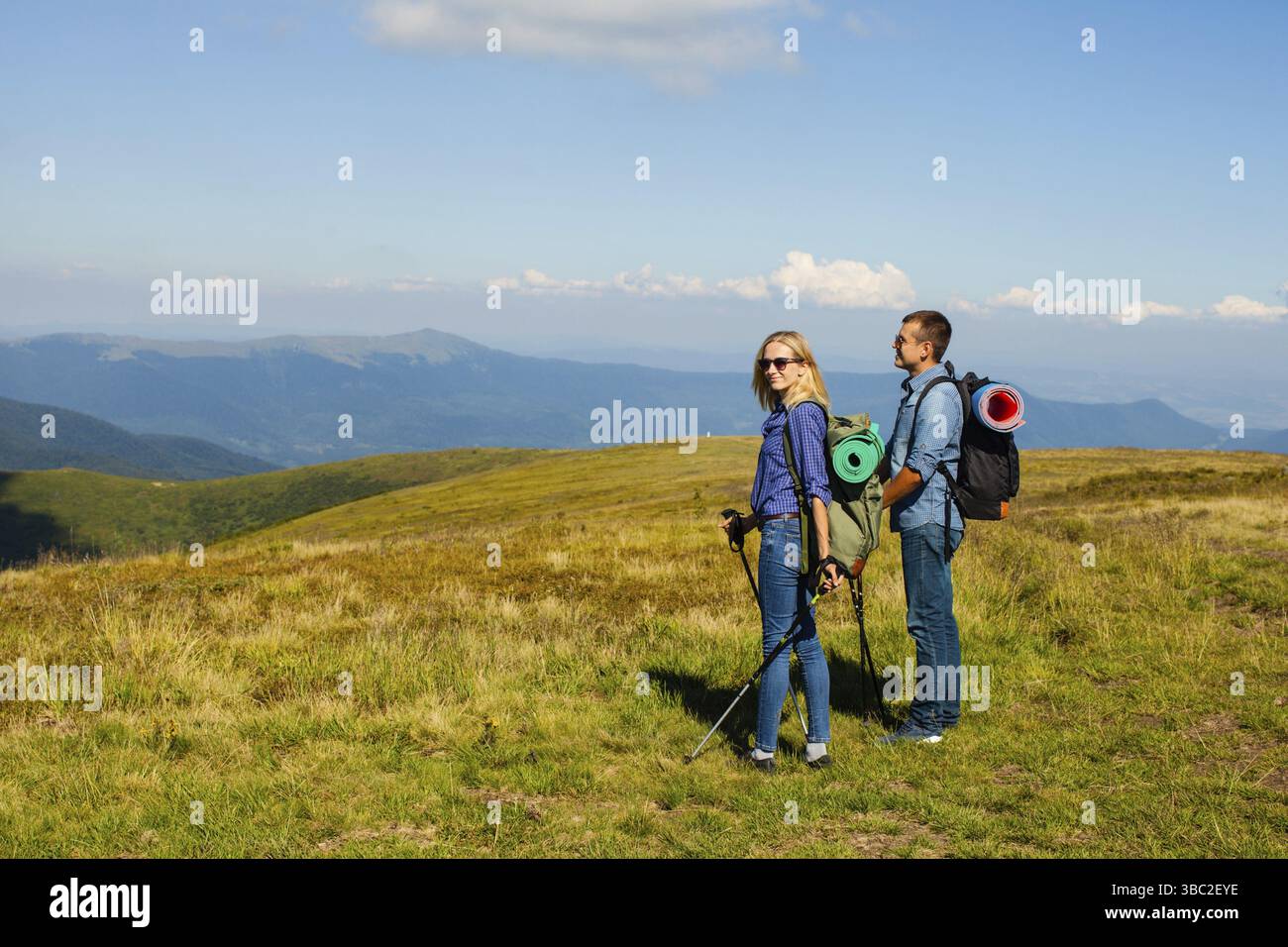 Couple heureux avec des bâtons de marche et des sacs à dos dans les mountans Banque D'Images