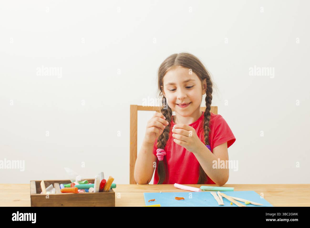 Girl jouer avec de la pâte à modeler colorée à tha tableau à la garderie. Kid sculps avec porcelaine froide Banque D'Images