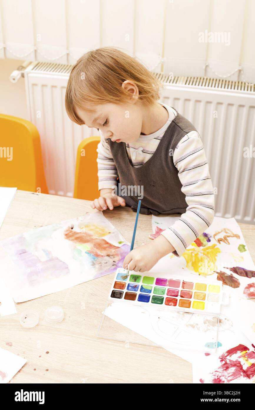 Fille, c'est peindre avec un pinceau et d'aquarelles sur papier dans le jardin d'enfants Banque D'Images