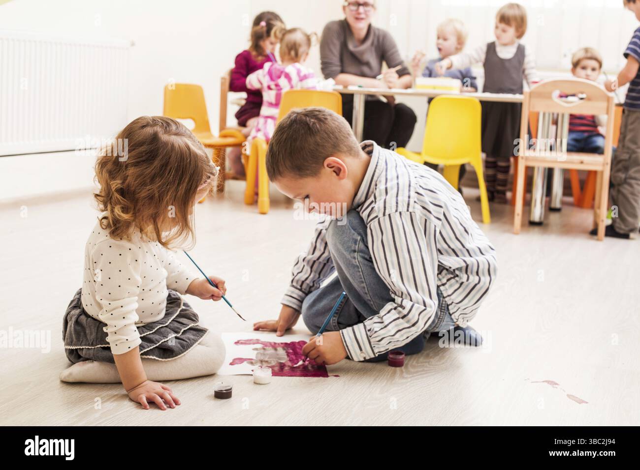 Les enfants sont la peinture avec un pinceau et d'aquarelles sur papier dans le jardin d'enfants Banque D'Images