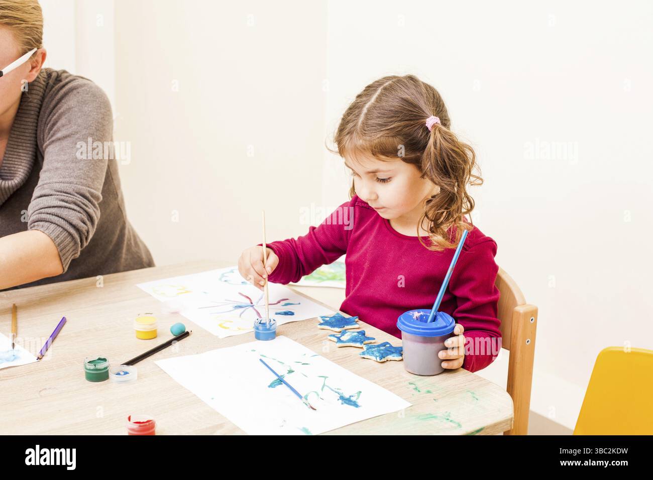 Fille, c'est peindre avec un pinceau et de la gouache sur un chiffres d'argile. Des décorations de noël faites à la main dans le jardin d'enfants Banque D'Images