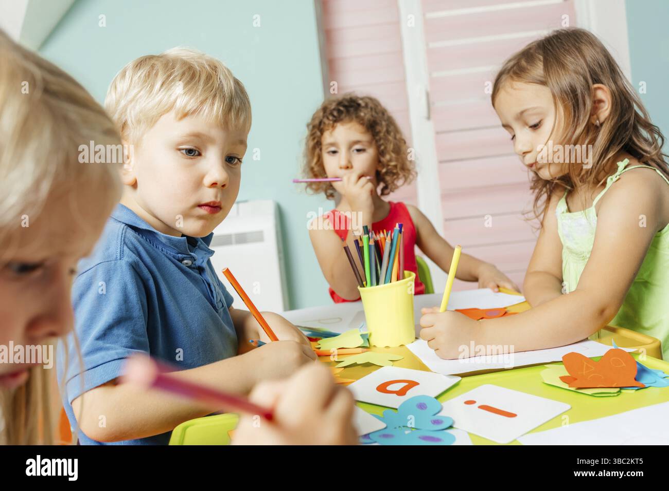 Gros plan enfants concentrés pendant les leçons d'anglais apprentissage alphabet. De charmants enfants apprenant des lettres anglaises à la maternelle. Concept d'éducation précoce Banque D'Images
