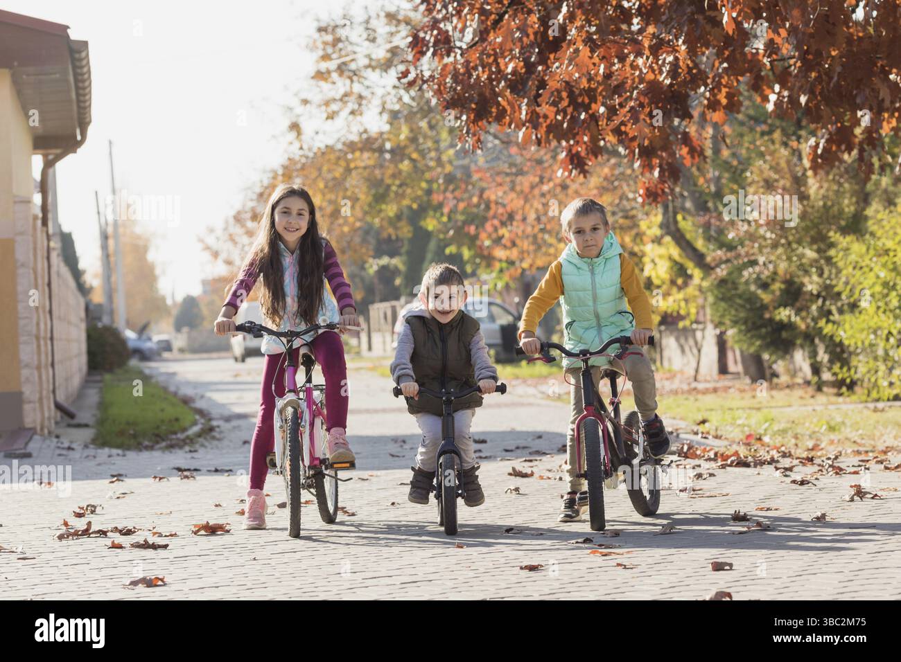 Les enfants frères et sœurs sont prêts pour la première compétition de cyclisme. Les enfants font du vélo d'appartement et des vélos, jour d'automne ensoleillé Banque D'Images