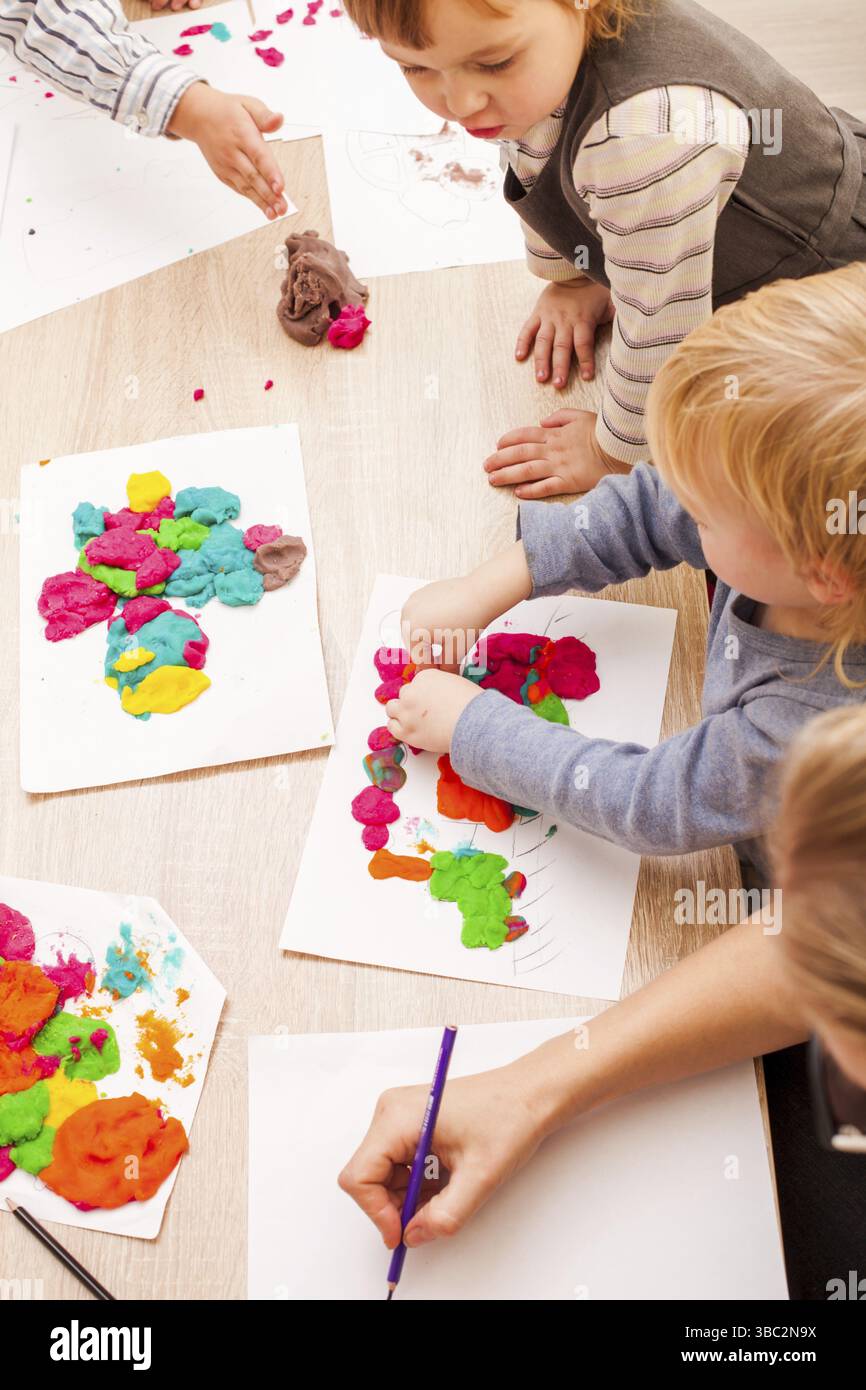 Les enfants jouent avec de l'argile à modeler sur la table Banque D'Images