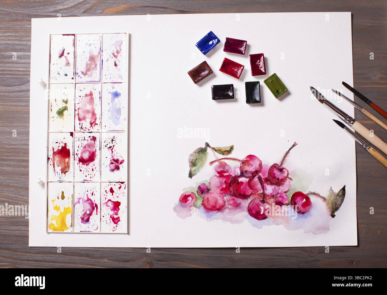 Œuvres d'art, peintures à l'aquarelle cerises avec outils de dessin sur une table en bois Banque D'Images