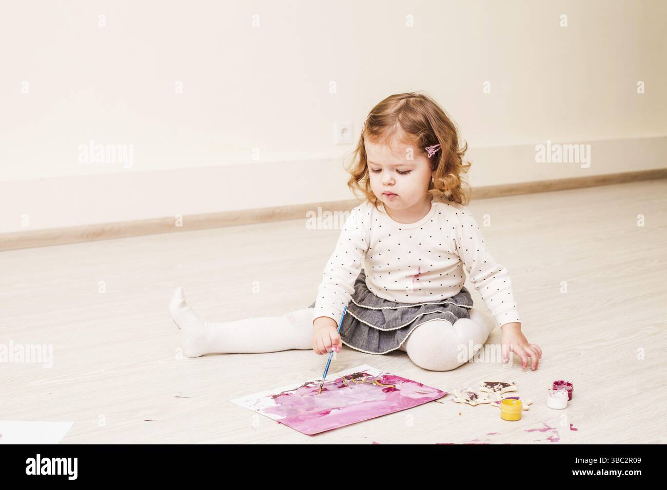 Fille, c'est peindre avec un pinceau et gouache sur papier sur le plancher Banque D'Images