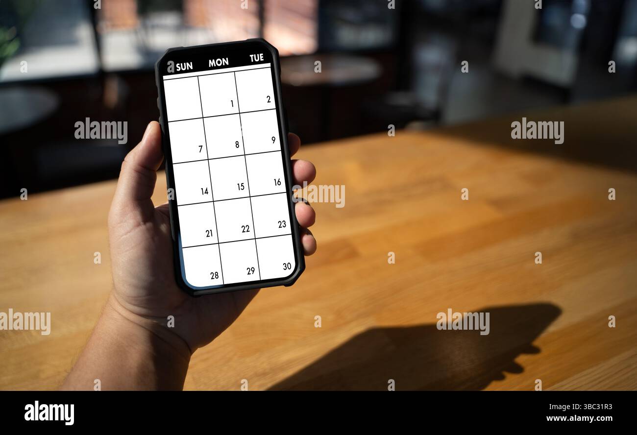 Une personne de calendrier 2025 tenant un smartphone affichant l'application de calendrier avec une grille vierge pour la planification ou la planification, cadre intérieur confortable avec un éclairage chaud Banque D'Images