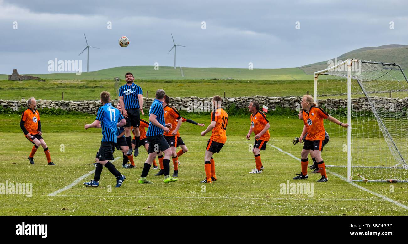 Pierowall, Westray, Orcades, Écosse, Royaume-Uni. Papa Westray v Sanday 2nd leg football matc in Orkney amateur Football Association League ou Orcadian Cup : la famille Houston trigénérationnelle) dans l'équipe de Papa Westray (alias les Doondies en maillots orange) allant dans l'âge de 63 à 19 ans, avec une population de 90 et aucun terrain de football à pratiquer sur perdre 7-1 ayant perdu 6-0 dans la 1ère manche. Ils étaient ravis de marquer un but avec un penalty dans les dernières minutes du match. De nombreux habitants de Papa Westray sont venus de l'île pour les soutenir. Crédit : Sally Anderson/Alamy Live News Banque D'Images