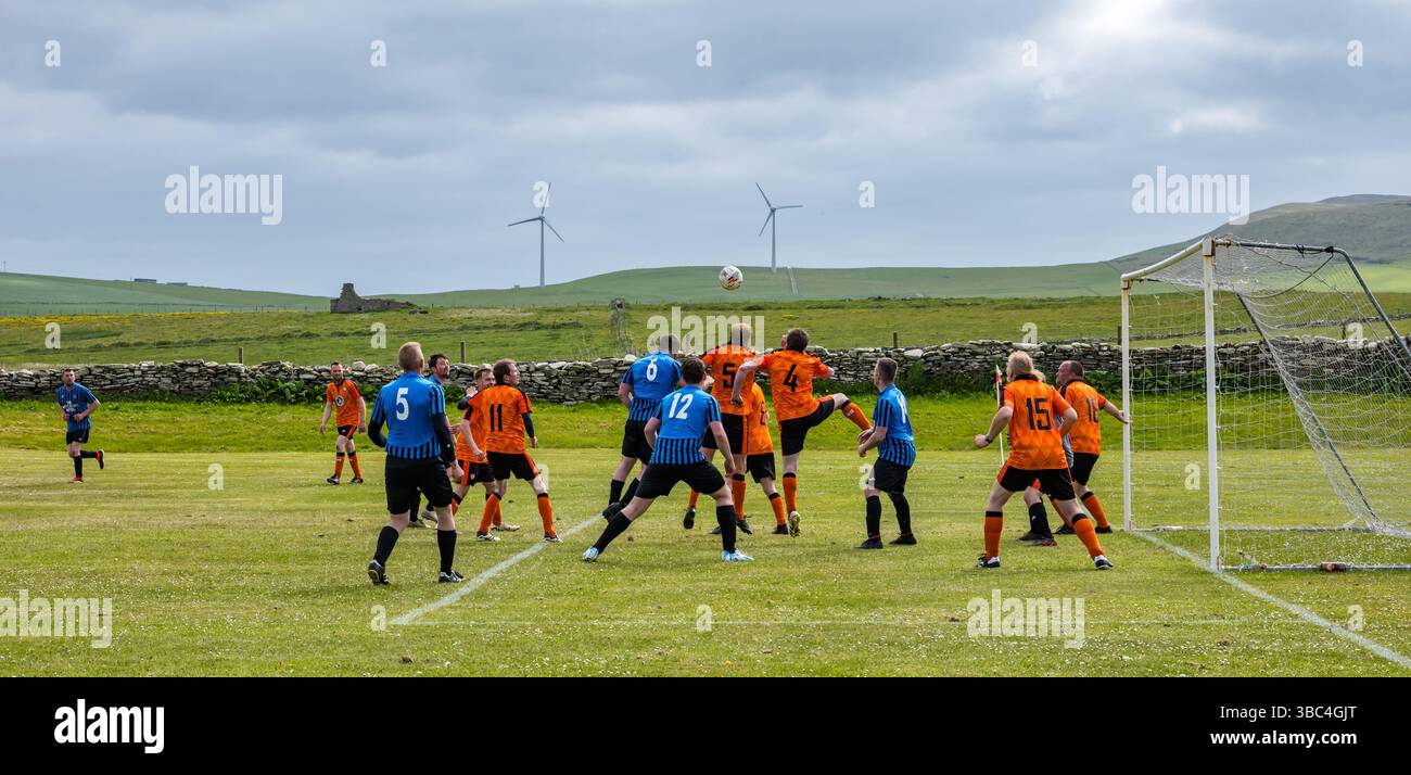 Pierowall, Westray, Orcades, Écosse, Royaume-Uni. Papa Westray v Sanday 2nd leg football matc in Orkney amateur Football Association League ou Orcadian Cup : la famille Houston trigénérationnelle) dans l'équipe de Papa Westray (alias les Doondies en maillots orange) allant dans l'âge de 63 à 19 ans, avec une population de 90 et aucun terrain de football à pratiquer sur perdre 7-1 ayant perdu 6-0 dans la 1ère manche. Ils étaient ravis de marquer un but avec un penalty dans les dernières minutes du match. De nombreux habitants de Papa Westray sont venus de l'île pour les soutenir. Crédit : Sally Anderson/Alamy Live News Banque D'Images