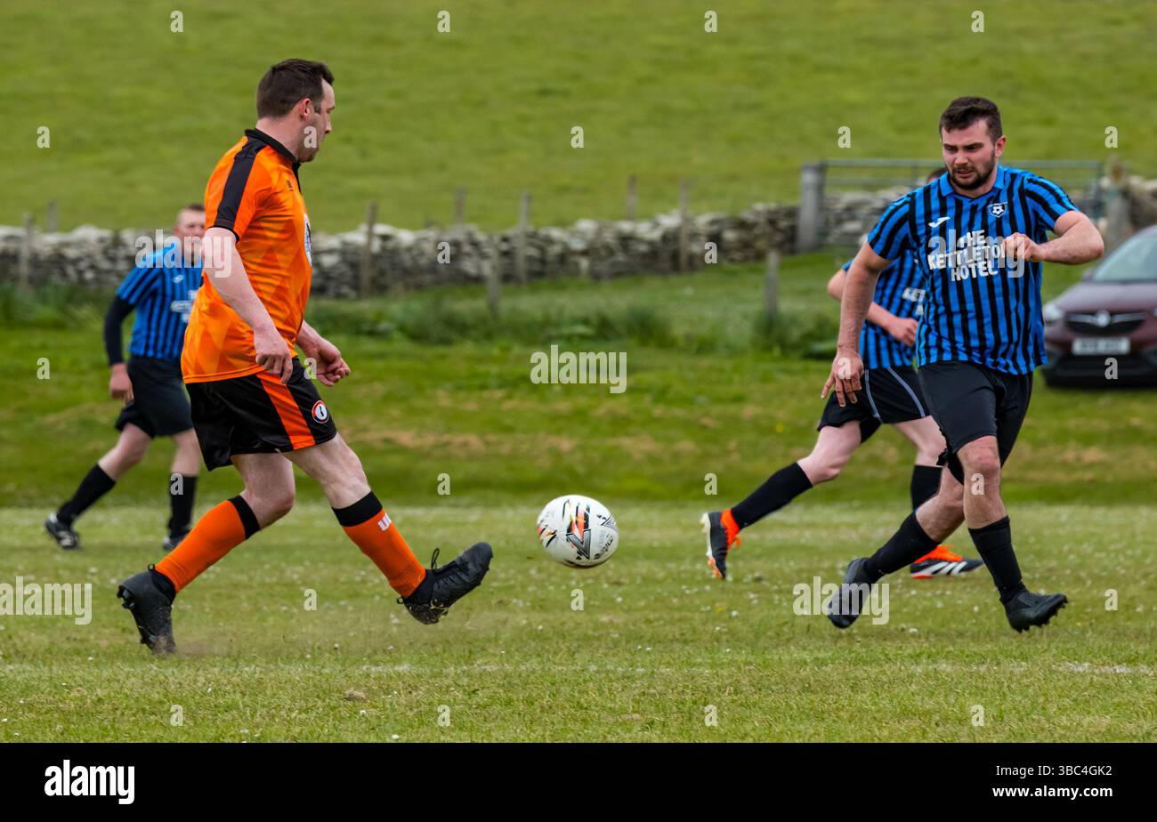 Pierowall, Westray, Orcades, Écosse, Royaume-Uni. Papa Westray v Sanday 2nd leg football matc in Orkney amateur Football Association League ou Orcadian Cup : la famille Houston trigénérationnelle) dans l'équipe de Papa Westray (alias les Doondies en maillots orange) allant dans l'âge de 63 à 19 ans, avec une population de 90 et aucun terrain de football à pratiquer sur perdre 7-1 ayant perdu 6-0 dans la 1ère manche. Ils étaient ravis de marquer un but avec un penalty dans les dernières minutes du match. De nombreux habitants de Papa Westray sont venus de l'île pour les soutenir. Crédit : Sally Anderson/Alamy Live News Banque D'Images