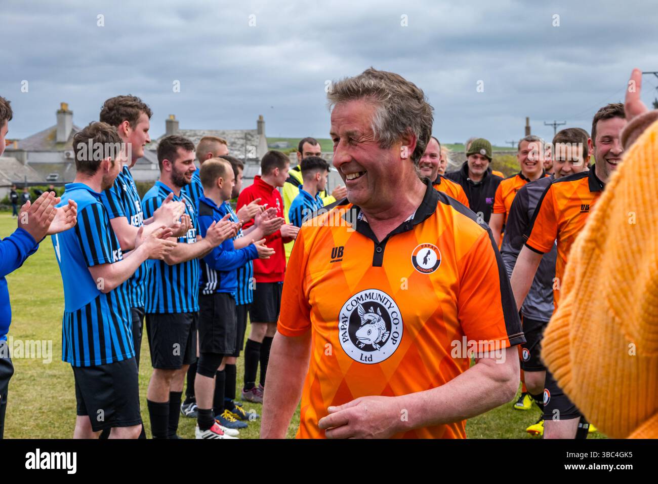 Pierowall, Westray, Orcades, Écosse, Royaume-Uni. Papa Westray v Sanday 2nd leg football matc in Orkney amateur Football Association League ou Orcadian Cup : la famille Houston trigénérationnelle) dans l'équipe de Papa Westray (alias les Doondies en maillots orange) allant dans l'âge de 63 à 19 ans, avec une population de 90 et aucun terrain de football à pratiquer sur perdre 7-1 ayant perdu 6-0 dans la 1ère manche. Ils étaient ravis de marquer un but avec un penalty dans les dernières minutes du match. De nombreux habitants de Papa Westray sont venus de l'île pour les soutenir. Crédit : Sally Anderson/Alamy Live News Banque D'Images