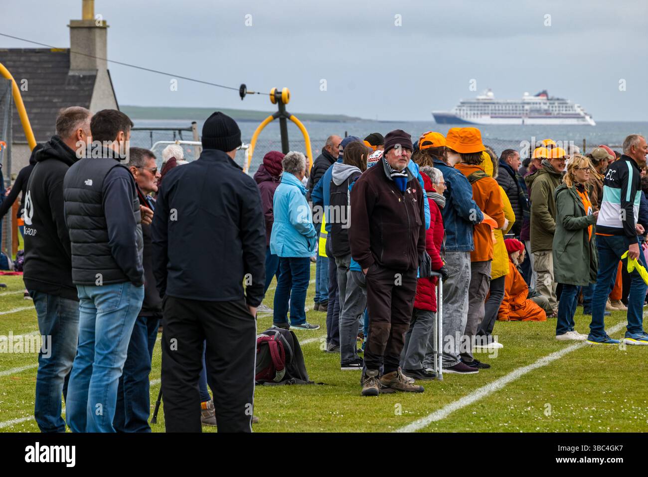 Pierowall, Westray, Orcades, Écosse, Royaume-Uni. Papay Westray v Sanday 2nd leg football match ligue Orkney amateur Football Association ou Orcadian Parish Cup : L'équipe trigénérationnelle (dans la famille Houston) de Papa Westray aka les Doondies en maillots orange vont de 63 à 19 ans, avec une population de 90 et aucun terrain de football à pratiquer perdre 7-1 ayant perdu 6-0 dans la 1ère manche. Ils étaient ravis de marquer un but avec un penalty dans les dernières minutes du match. De nombreux habitants de Papa Westray sont venus les appuyer. Pic : les supporters de papa en chapeaux orange avec le bateau de croisière Hanseatic Spirit. Crédit Banque D'Images