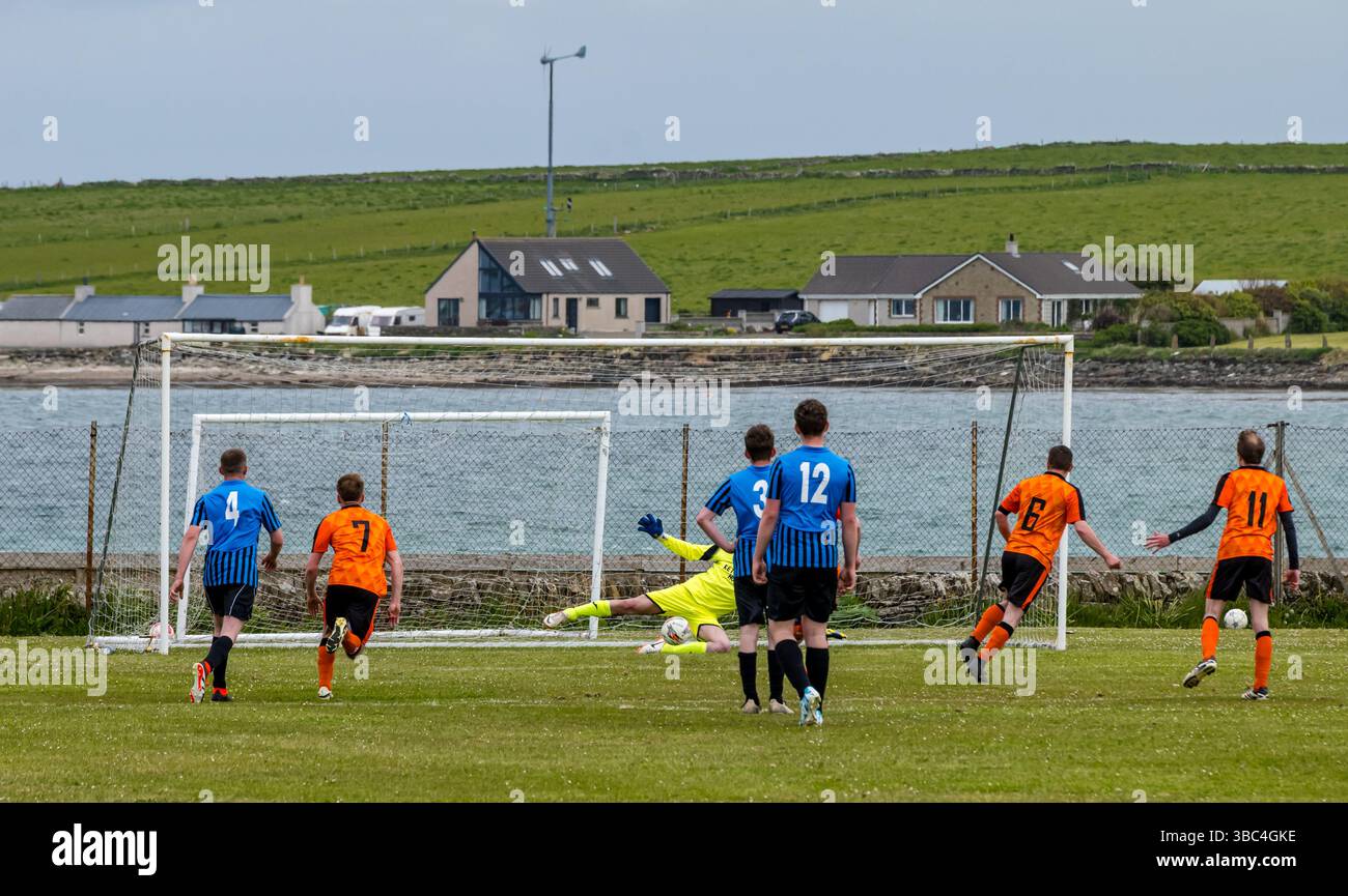 Pierowall, Westray, Orcades, Écosse, Royaume-Uni. Papa Westray v Sanday 2ème match de football matc dans la ligue Orkney amateur Football Association ou Coupe Orcadienne : la famille Houston trigénérationnelle) dans l'équipe de Papa Westray (alias les Doondies en maillots orange) allant dans l'âge de 63 à 19 ans, avec une population de 90 et aucun terrain de football à pratiquer sur perdre 7-1 ayant perdu 6-0 dans la 1ère manche le 6 mai. Ils étaient ravis de marquer un but avec un penalty dans les dernières minutes du match. De nombreux habitants de Papa Westray sont venus de l'île pour les soutenir. Pic : le but de Papay Banque D'Images