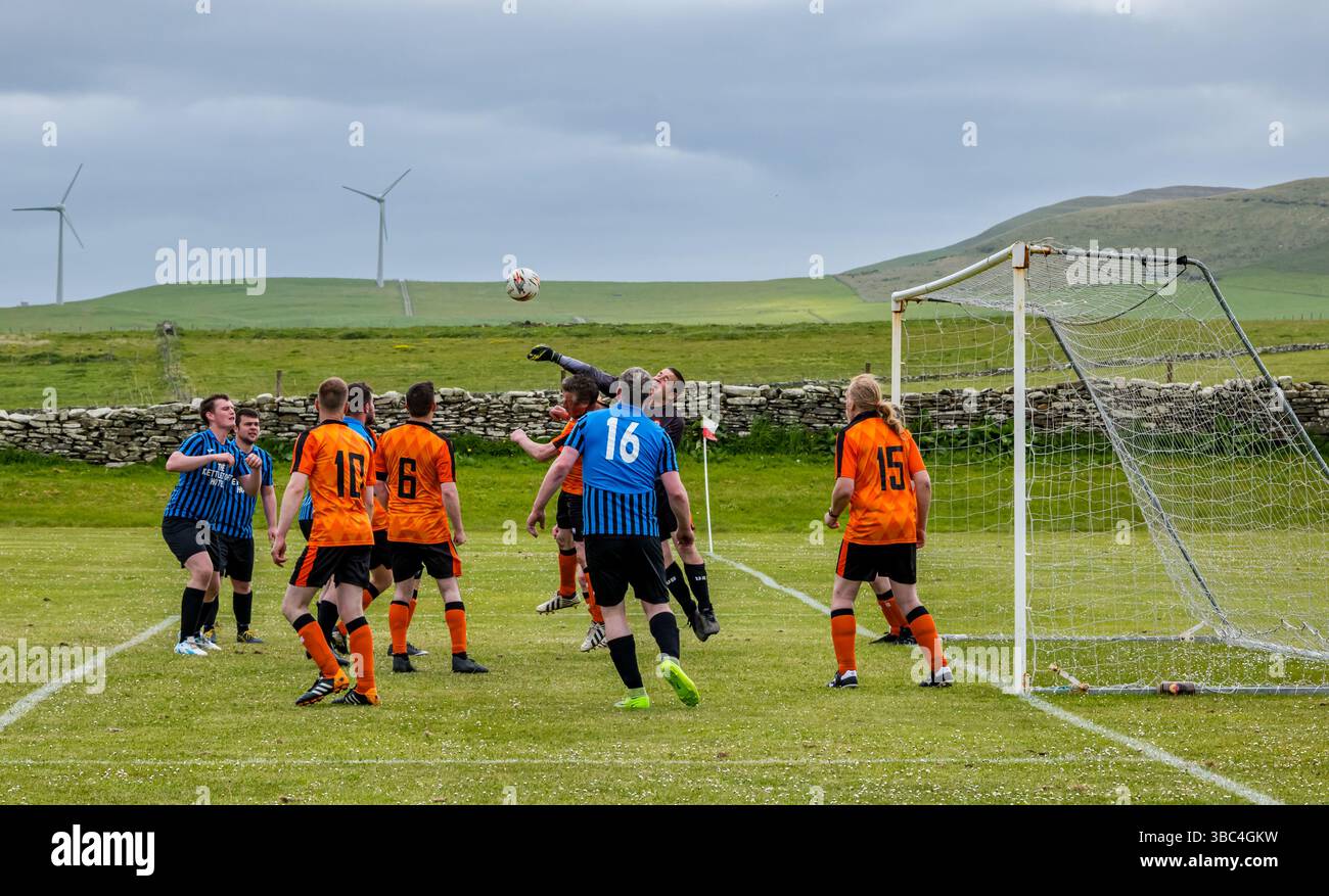 Pierowall, Westray, Orcades, Écosse, Royaume-Uni. Papa Westray v Sanday 2nd leg football matc in Orkney amateur Football Association League ou Orcadian Cup : la famille Houston trigénérationnelle) dans l'équipe de Papa Westray (alias les Doondies en maillots orange) allant dans l'âge de 63 à 19 ans, avec une population de 90 et aucun terrain de football à pratiquer sur perdre 7-1 ayant perdu 6-0 dans la 1ère manche. Ils étaient ravis de marquer un but avec un penalty dans les dernières minutes du match. De nombreux habitants de Papa Westray sont venus de l'île pour les soutenir. Crédit : Sally Anderson/Alamy Live News Banque D'Images