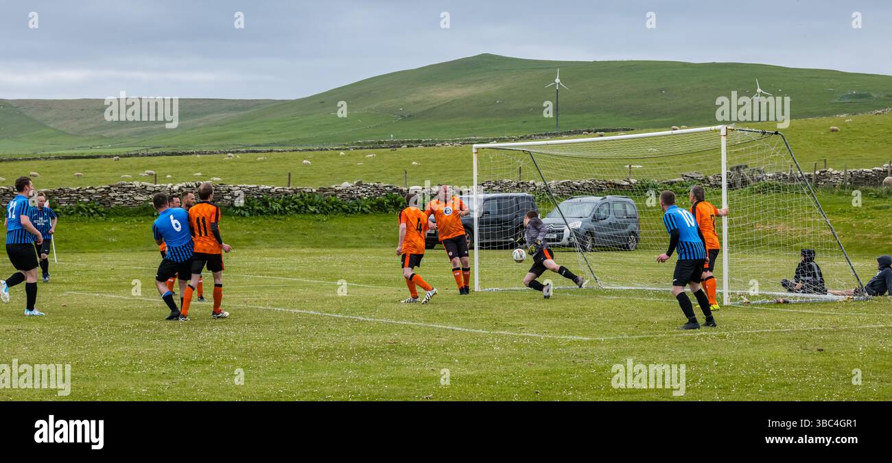Pierowall, Westray, Orcades, Écosse, Royaume-Uni. Papa Westray v Sanday 2nd leg football matc in Orkney amateur Football Association League ou Orcadian Cup : la famille Houston trigénérationnelle) dans l'équipe de Papa Westray (alias les Doondies en maillots orange) allant dans l'âge de 63 à 19 ans, avec une population de 90 et aucun terrain de football à pratiquer sur perdre 7-1 ayant perdu 6-0 dans la 1ère manche. Ils étaient ravis de marquer un but avec un penalty dans les dernières minutes du match. De nombreux habitants de Papa Westray sont venus de l'île pour les soutenir. Crédit : Sally Anderson/Alamy Live News Banque D'Images