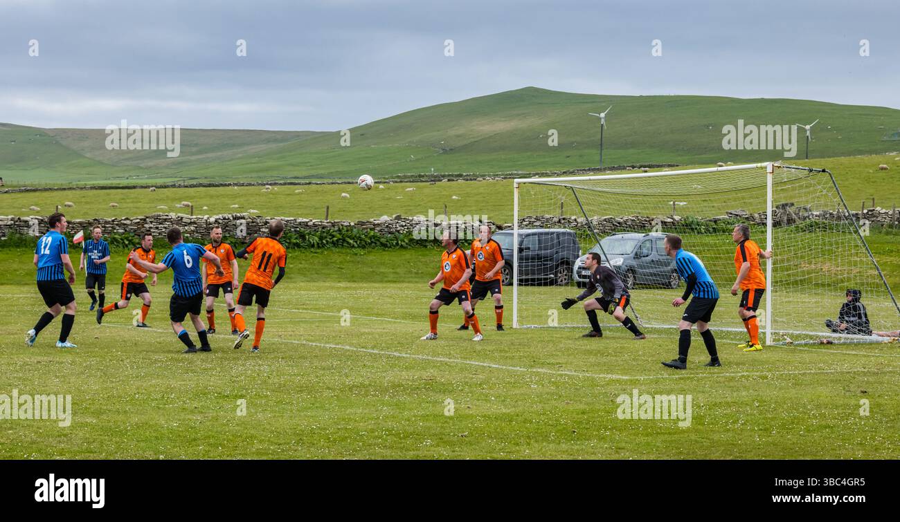 Pierowall, Westray, Orcades, Écosse, Royaume-Uni. Papa Westray v Sanday 2nd leg football matc in Orkney amateur Football Association League ou Orcadian Cup : la famille Houston trigénérationnelle) dans l'équipe de Papa Westray (alias les Doondies en maillots orange) allant dans l'âge de 63 à 19 ans, avec une population de 90 et aucun terrain de football à pratiquer sur perdre 7-1 ayant perdu 6-0 dans la 1ère manche. Ils étaient ravis de marquer un but avec un penalty dans les dernières minutes du match. De nombreux habitants de Papa Westray sont venus de l'île pour les soutenir. Crédit : Sally Anderson/Alamy Live News Banque D'Images