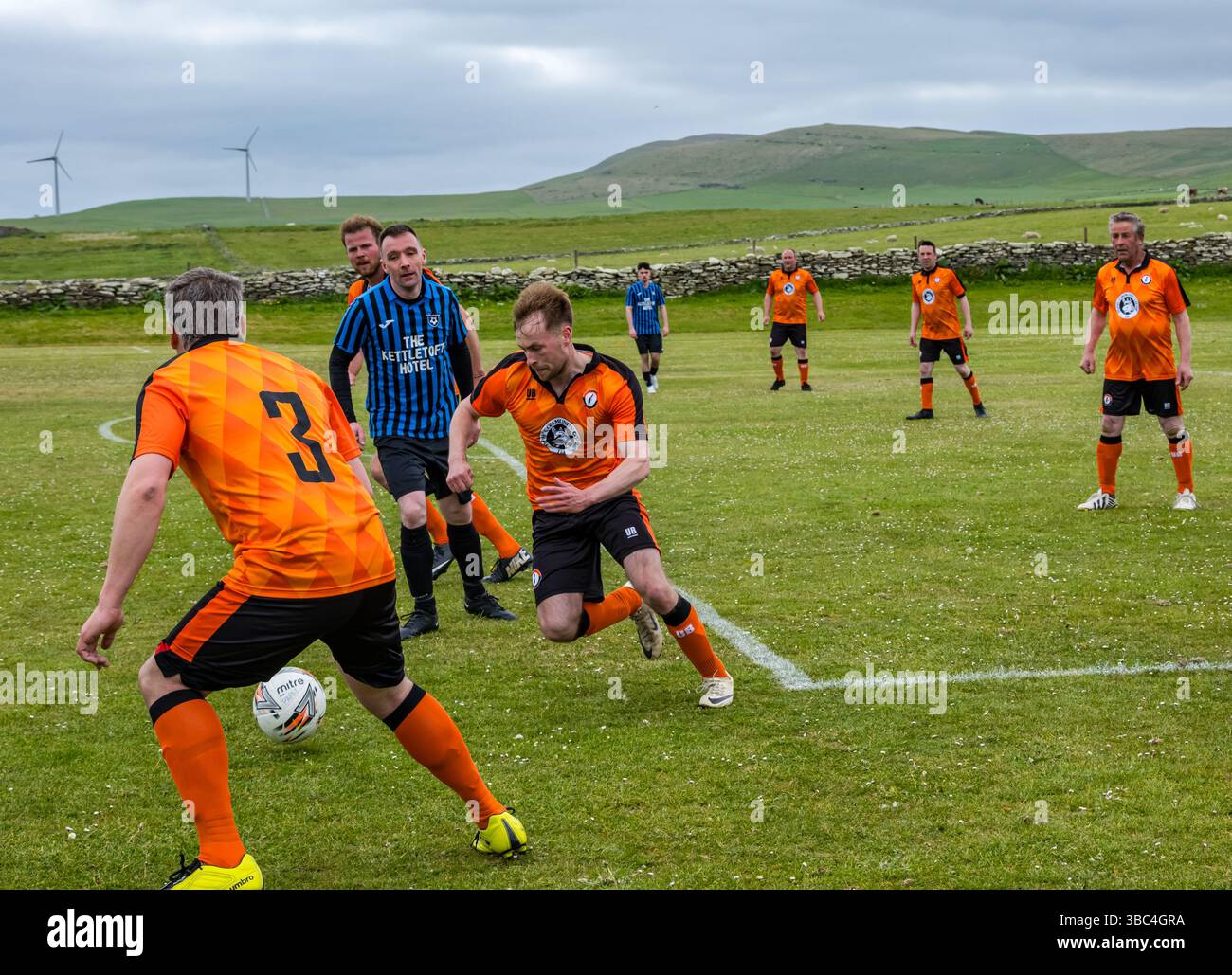 Pierowall, Westray, Orcades, Écosse, Royaume-Uni. Papa Westray v Sanday 2nd leg football matc in Orkney amateur Football Association League ou Orcadian Cup : la famille Houston trigénérationnelle) dans l'équipe de Papa Westray (alias les Doondies en maillots orange) allant dans l'âge de 63 à 19 ans, avec une population de 90 et aucun terrain de football à pratiquer sur perdre 7-1 ayant perdu 6-0 dans la 1ère manche. Ils étaient ravis de marquer un but avec un penalty dans les dernières minutes du match. De nombreux habitants de Papa Westray sont venus de l'île pour les soutenir. Crédit : Sally Anderson/Alamy Live News Banque D'Images