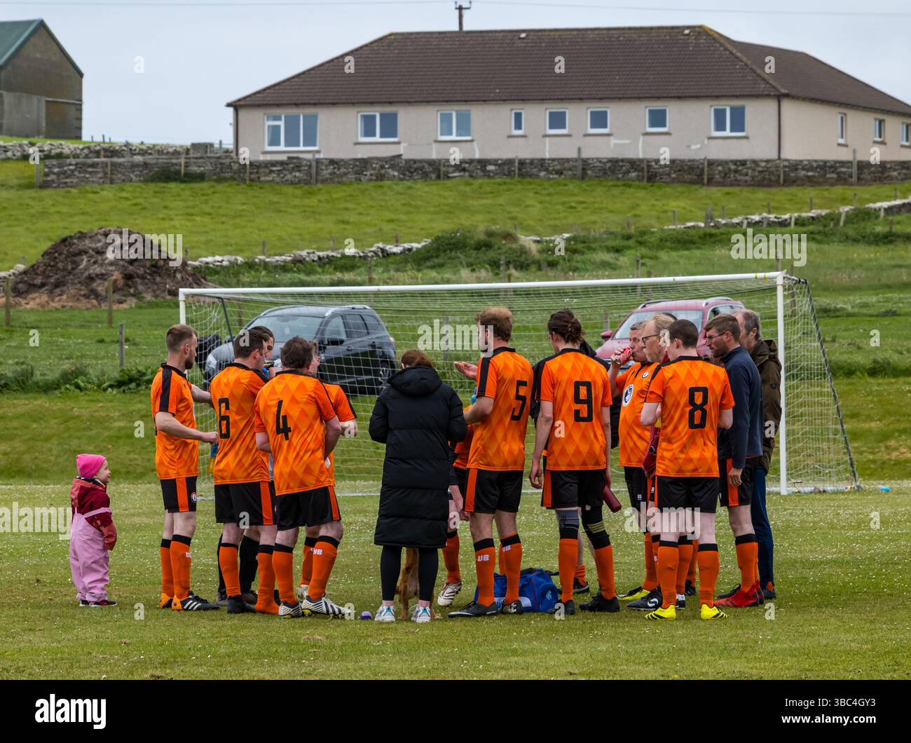 Pierowall, Westray, Orcades, Écosse, Royaume-Uni. Papa Westray v Sanday 2nd leg football matc in Orkney amateur Football Association League ou Orcadian Cup : la famille Houston trigénérationnelle) dans l'équipe de Papa Westray (alias les Doondies en maillots orange) allant dans l'âge de 63 à 19 ans, avec une population de 90 et aucun terrain de football à pratiquer sur perdre 7-1 ayant perdu 6-0 dans la 1ère manche. Ils étaient ravis de marquer un but avec un penalty dans les dernières minutes du match. De nombreux habitants de Papa Westray sont venus de l'île pour les soutenir. Crédit : Sally Anderson/Alamy Live News Banque D'Images