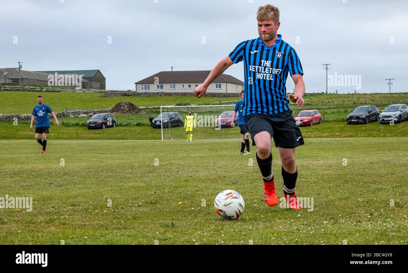 Pierowall, Westray, Orcades, Écosse, Royaume-Uni. Papa Westray v Sanday 2nd leg football matc in Orkney amateur Football Association League ou Orcadian Cup : la famille Houston trigénérationnelle) dans l'équipe de Papa Westray (alias les Doondies en maillots orange) allant dans l'âge de 63 à 19 ans, avec une population de 90 et aucun terrain de football à pratiquer sur perdre 7-1 ayant perdu 6-0 dans la 1ère manche. Ils étaient ravis de marquer un but avec un penalty dans les dernières minutes du match. De nombreux habitants de Papa Westray sont venus de l'île pour les soutenir. Crédit : Sally Anderson/Alamy Live News Banque D'Images