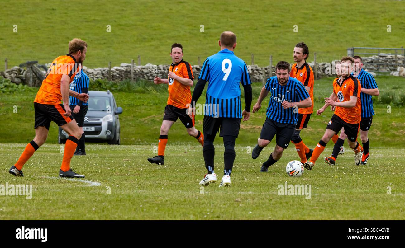 Pierowall, Westray, Orcades, Écosse, Royaume-Uni. Papa Westray v Sanday 2nd leg football matc in Orkney amateur Football Association League ou Orcadian Cup : la famille Houston trigénérationnelle) dans l'équipe de Papa Westray (alias les Doondies en maillots orange) allant dans l'âge de 63 à 19 ans, avec une population de 90 et aucun terrain de football à pratiquer sur perdre 7-1 ayant perdu 6-0 dans la 1ère manche. Ils étaient ravis de marquer un but avec un penalty dans les dernières minutes du match. De nombreux habitants de Papa Westray sont venus de l'île pour les soutenir. Crédit : Sally Anderson/Alamy Live News Banque D'Images