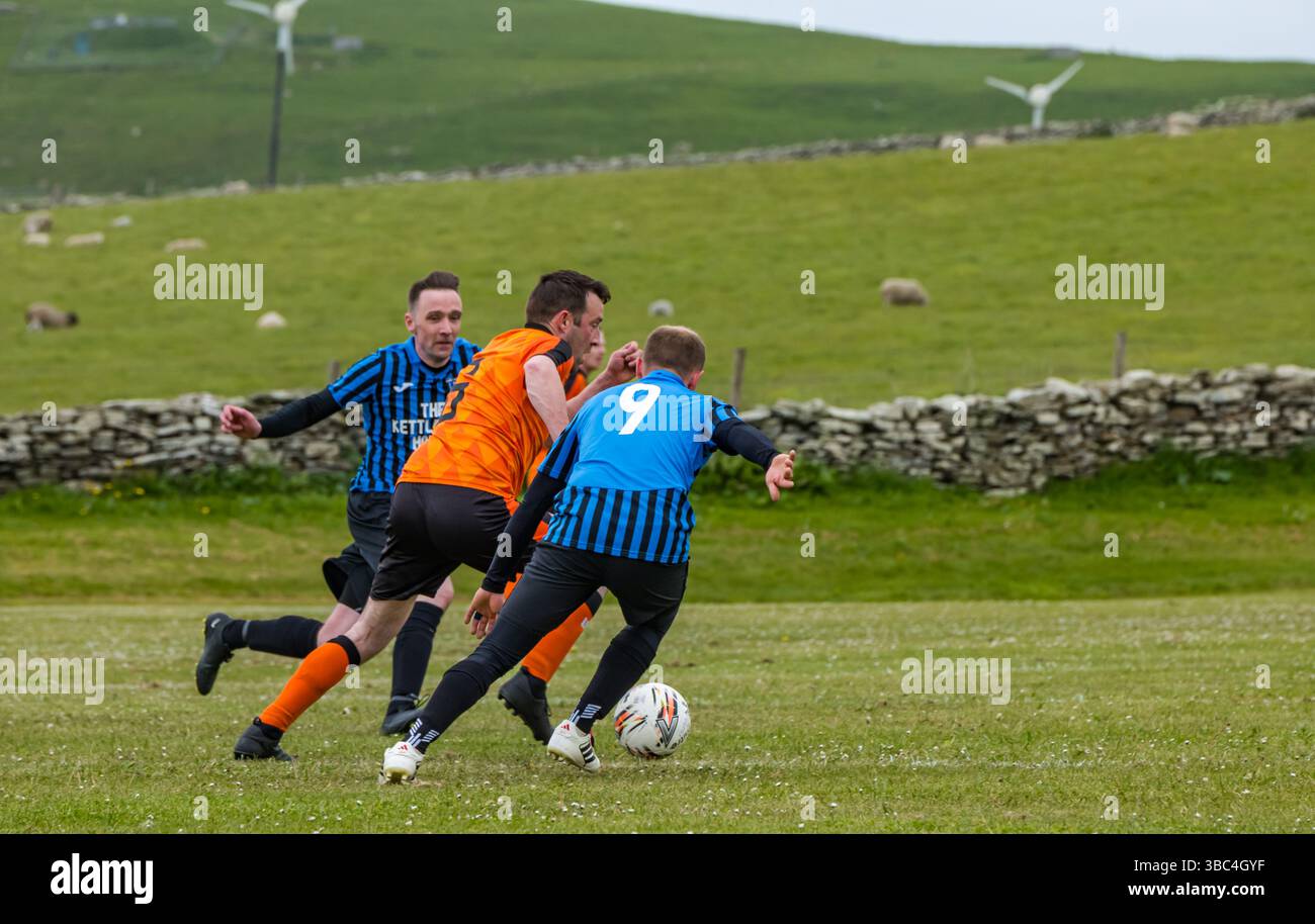 Pierowall, Westray, Orcades, Écosse, Royaume-Uni. Papa Westray v Sanday 2nd leg football matc in Orkney amateur Football Association League ou Orcadian Cup : la famille Houston trigénérationnelle) dans l'équipe de Papa Westray (alias les Doondies en maillots orange) allant dans l'âge de 63 à 19 ans, avec une population de 90 et aucun terrain de football à pratiquer sur perdre 7-1 ayant perdu 6-0 dans la 1ère manche. Ils étaient ravis de marquer un but avec un penalty dans les dernières minutes du match. De nombreux habitants de Papa Westray sont venus de l'île pour les soutenir. Crédit : Sally Anderson/Alamy Live News Banque D'Images