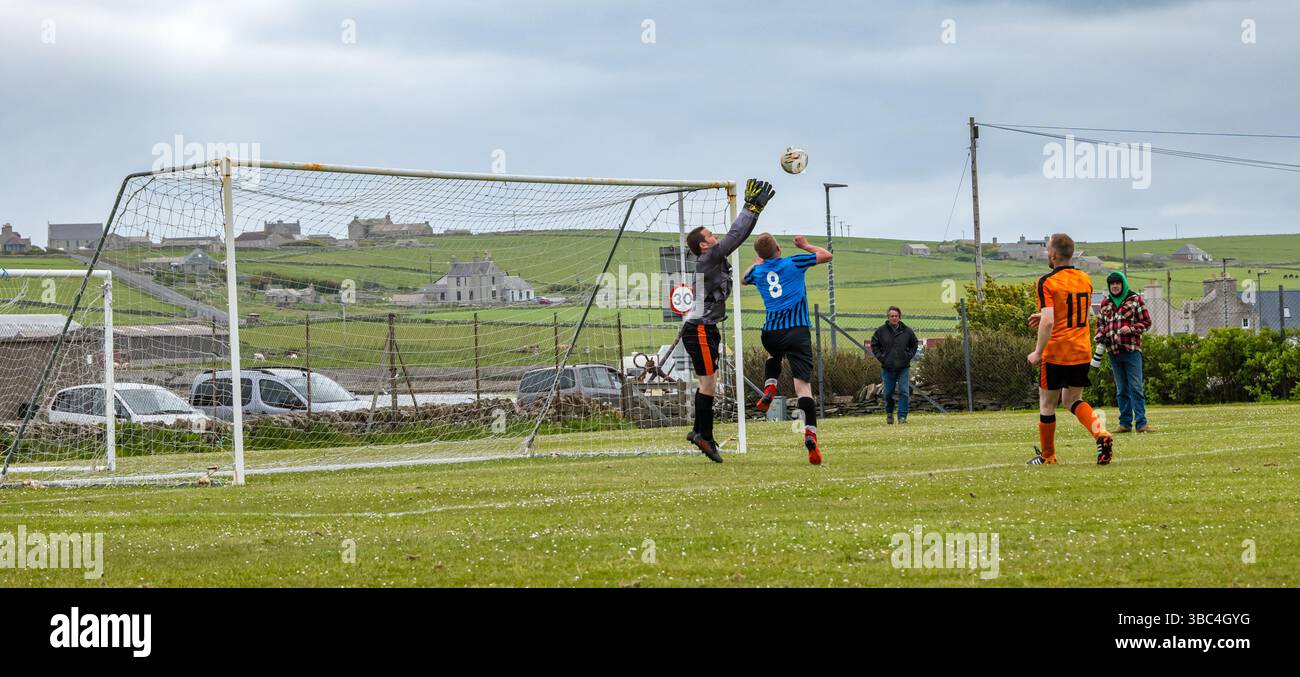 Pierowall, Westray, Orcades, Écosse, Royaume-Uni. Papa Westray v Sanday 2nd leg football matc in Orkney amateur Football Association League ou Orcadian Cup : la famille Houston trigénérationnelle) dans l'équipe de Papa Westray (alias les Doondies en maillots orange) allant dans l'âge de 63 à 19 ans, avec une population de 90 et aucun terrain de football à pratiquer sur perdre 7-1 ayant perdu 6-0 dans la 1ère manche. Ils étaient ravis de marquer un but avec un penalty dans les dernières minutes du match. De nombreux habitants de Papa Westray sont venus de l'île pour les soutenir. Crédit : Sally Anderson/Alamy Live News Banque D'Images