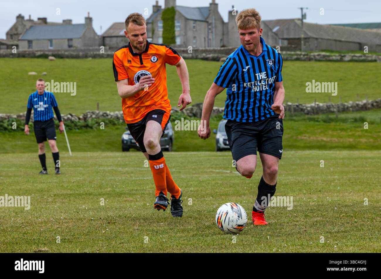 Pierowall, Westray, Orcades, Écosse, Royaume-Uni. Papa Westray v Sanday 2nd leg football matc in Orkney amateur Football Association League ou Orcadian Cup : la famille Houston trigénérationnelle) dans l'équipe de Papa Westray (alias les Doondies en maillots orange) allant dans l'âge de 63 à 19 ans, avec une population de 90 et aucun terrain de football à pratiquer sur perdre 7-1 ayant perdu 6-0 dans la 1ère manche. Ils étaient ravis de marquer un but avec un penalty dans les dernières minutes du match. De nombreux habitants de Papa Westray sont venus de l'île pour les soutenir. Crédit : Sally Anderson/Alamy Live News Banque D'Images