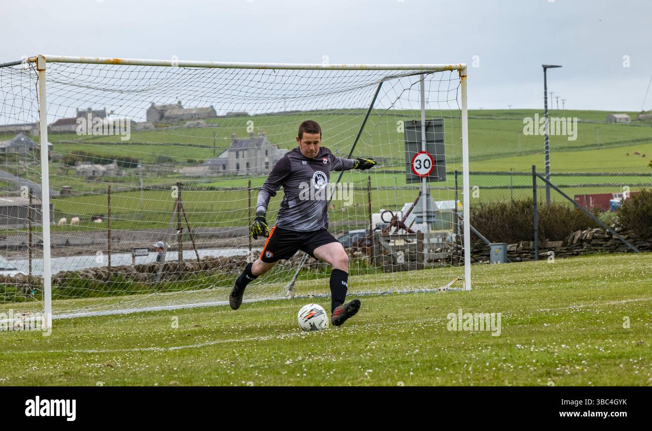 Pierowall, Westray, Orcades, Écosse, Royaume-Uni. Papa Westray v Sanday 2nd leg football matc in Orkney amateur Football Association League ou Orcadian Cup : la famille Houston trigénérationnelle) dans l'équipe de Papa Westray (alias les Doondies en maillots orange) allant dans l'âge de 63 à 19 ans, avec une population de 90 et aucun terrain de football à pratiquer sur perdre 7-1 ayant perdu 6-0 dans la 1ère manche. Ils étaient ravis de marquer un but avec un penalty dans les dernières minutes du match. De nombreux habitants de Papa Westray sont venus de l'île pour les soutenir. Crédit : Sally Anderson/Alamy Live News Banque D'Images