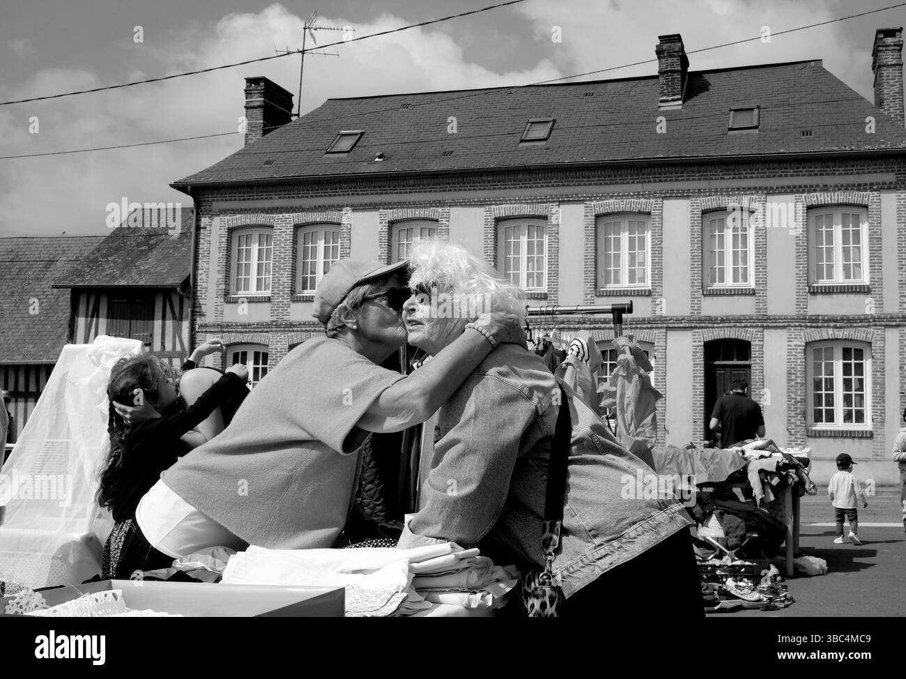 Un baiser de voeux traditionnel par des dames françaises à une Foire a tout ou vente de village à Genneville, Normandie, France Banque D'Images