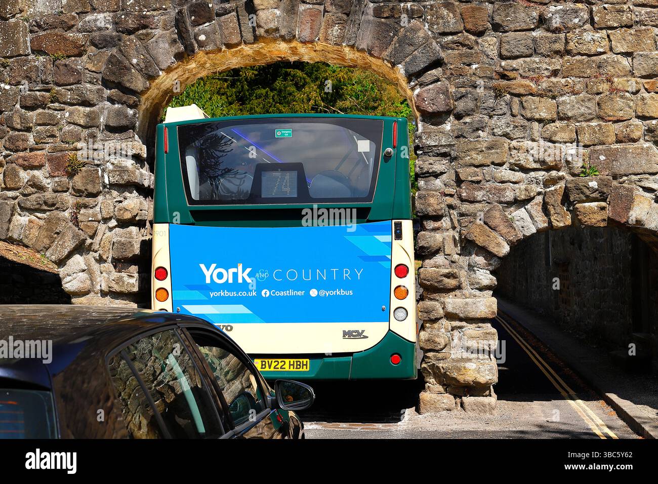 Le bus numéro 74 York & Country parvient à peine à passer par une étroite arche en pierre à Bolton Abbey dans le parc national des Yorkshire Dales. Banque D'Images