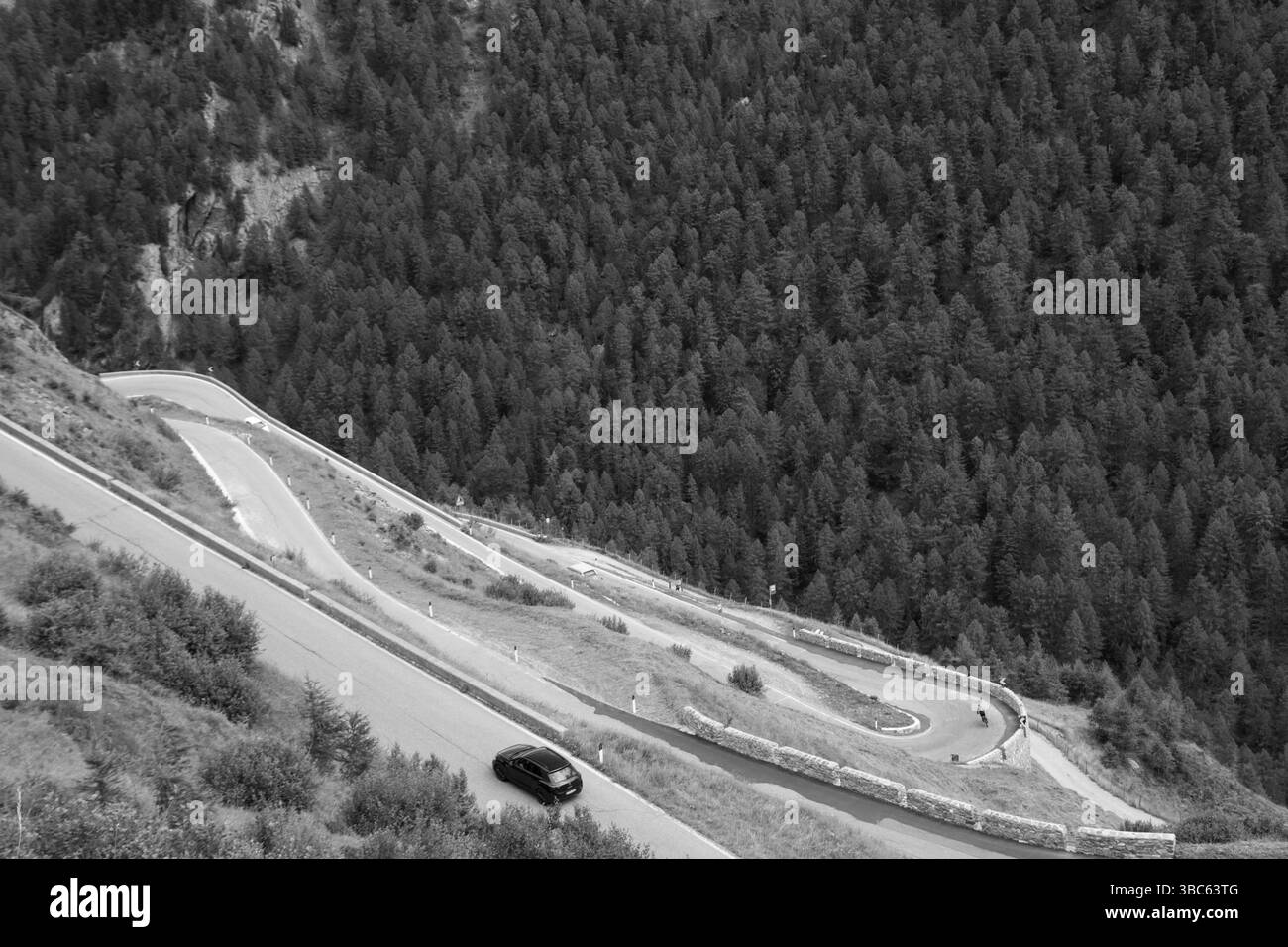 Noir et blanc détail vue à vol d'oiseau des épingles à cheveux de la route sinueuse vers le col de Timmelsjoch avec une voiture noire qui passe Banque D'Images