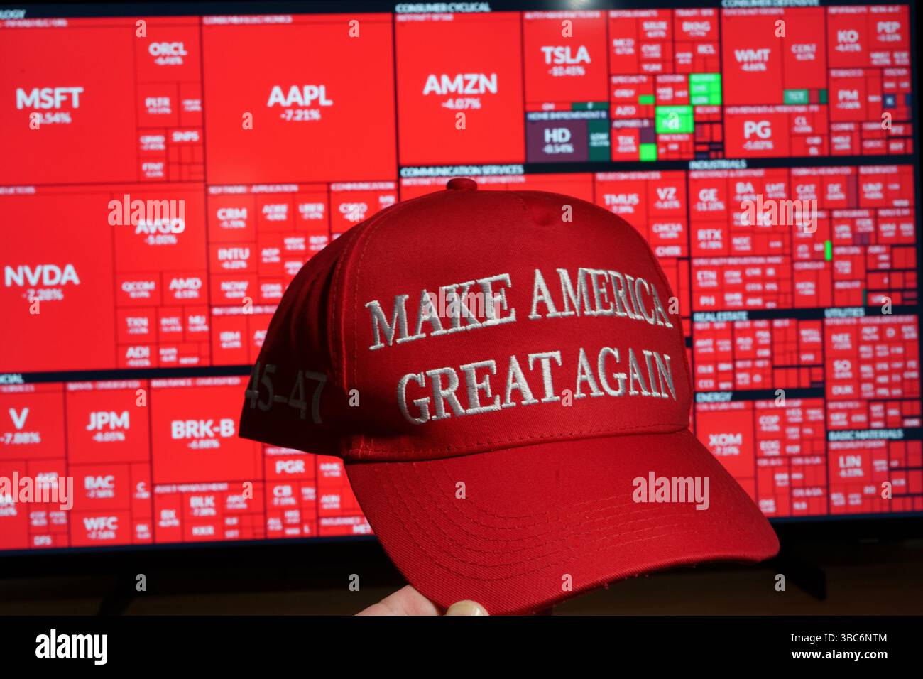 Make America Great Again cap rouge tenu devant une carte thermique de krach boursier montrant les pertes du S&P 500 dans tous les secteurs lorsque Trump a introduit des tarrifs Banque D'Images