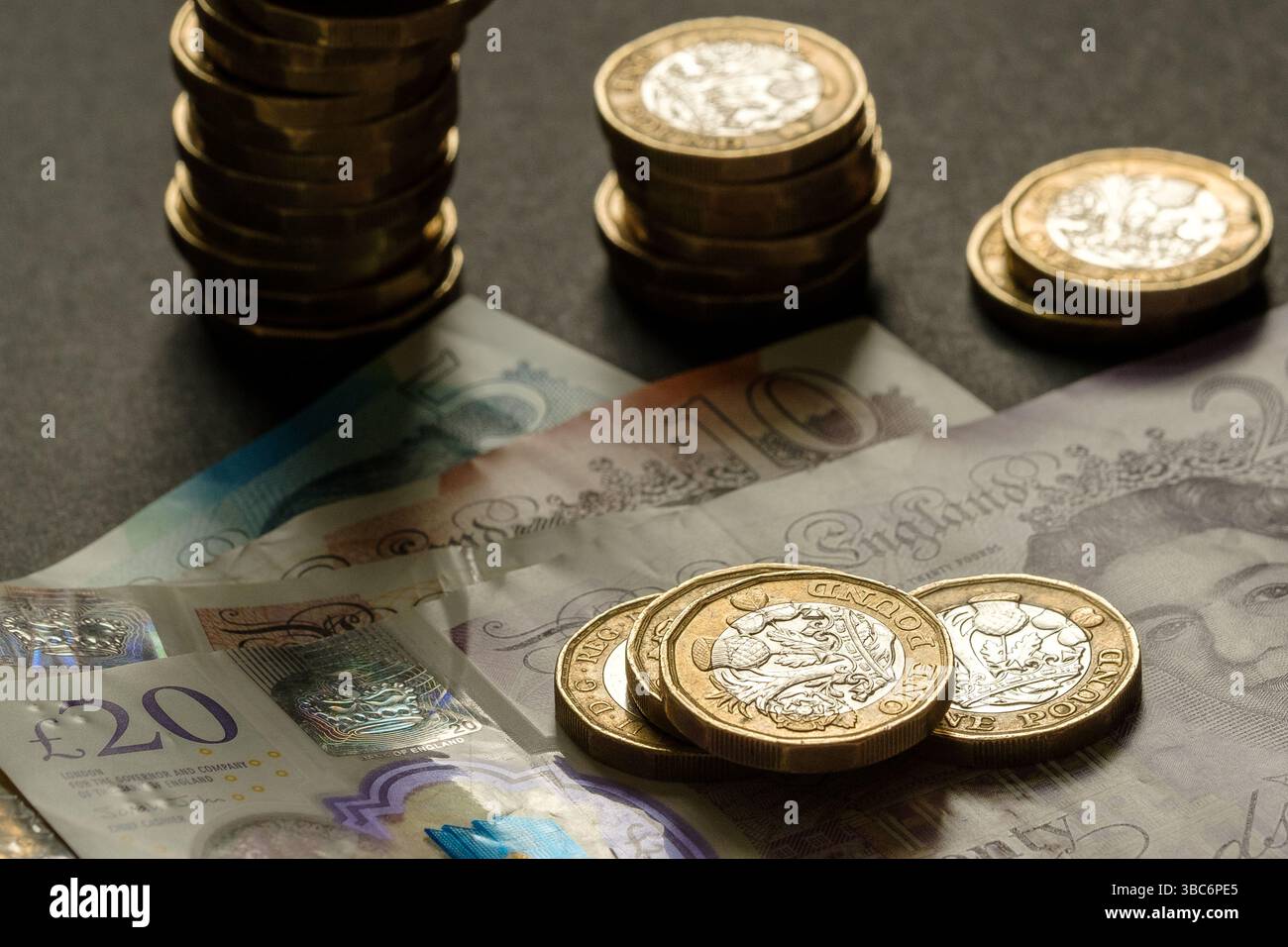 Piles de pièces britanniques d'une livre placées sur des billets de cinq, dix et vingt livres, symbolisant l'épargne, le budget et la richesse au Royaume-Uni, Stafford, Unite Banque D'Images