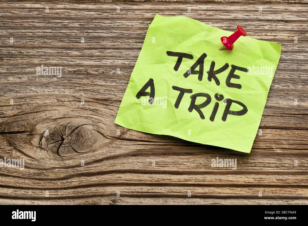 Prenez un voyage - note de rappel d'écriture manuscrite sur une note adhésive verte contre du bois grainé Banque D'Images