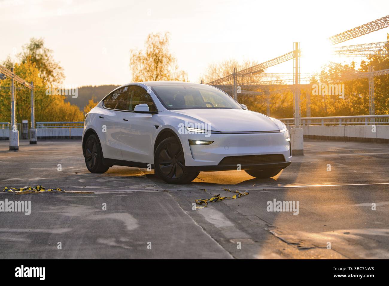 Une voiture blanche dans un parking avec une toile de fond automnale et coucher de soleil, Tesla nouveau modèle y Juniper, Nagold, Allemagne, Europe Banque D'Images