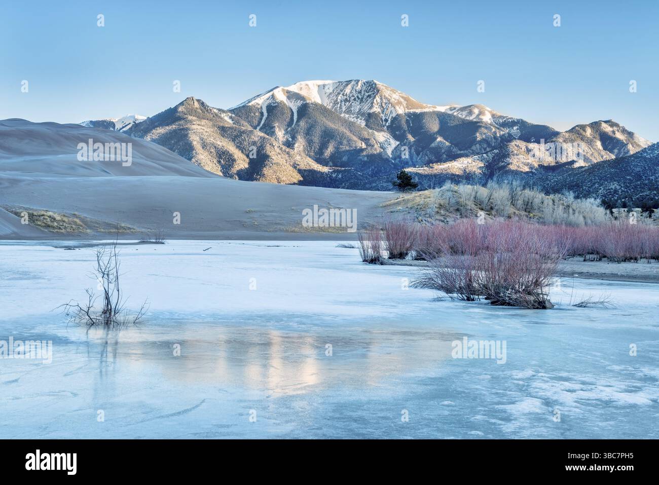 Sunrise over frozen Medano Creek avec Sangre de Cristo Mountains en arrière-plan, Great Sand Dunes National Park, Colorado Banque D'Images