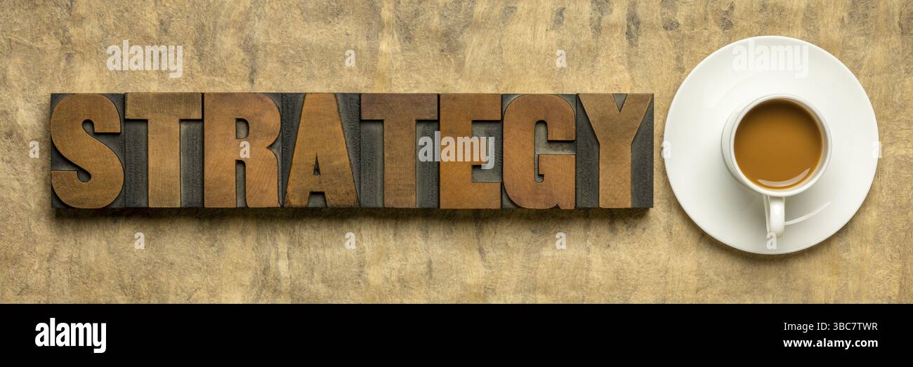 Mot de stratégie en type de bois typographique vintage contre du papier texturé fait à la main avec une tasse de café, concept de planification d'entreprise Banque D'Images