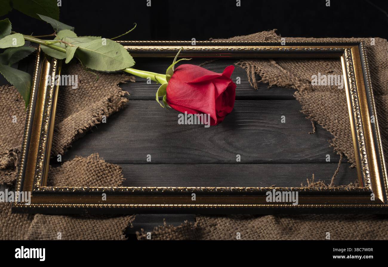 Dans un beau cadre, des morceaux de toile et une rose rouge sur fond de bois Banque D'Images