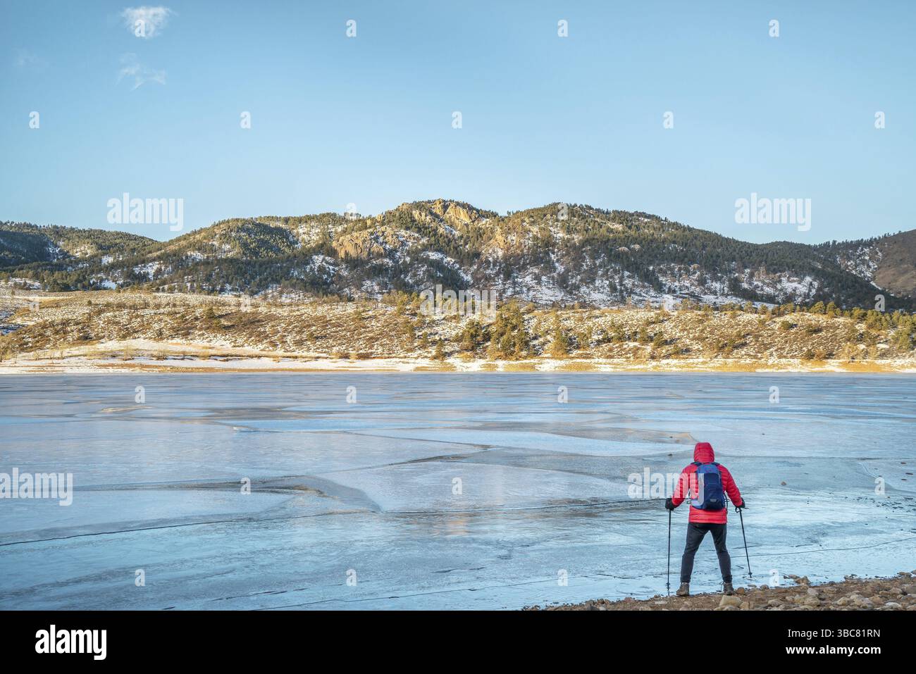 Randonneur mâle sur une rive du réservoir gelé de Horsetooth près de Fort Collins, Colorado avec Athurs's Rock en arrière-plan Banque D'Images